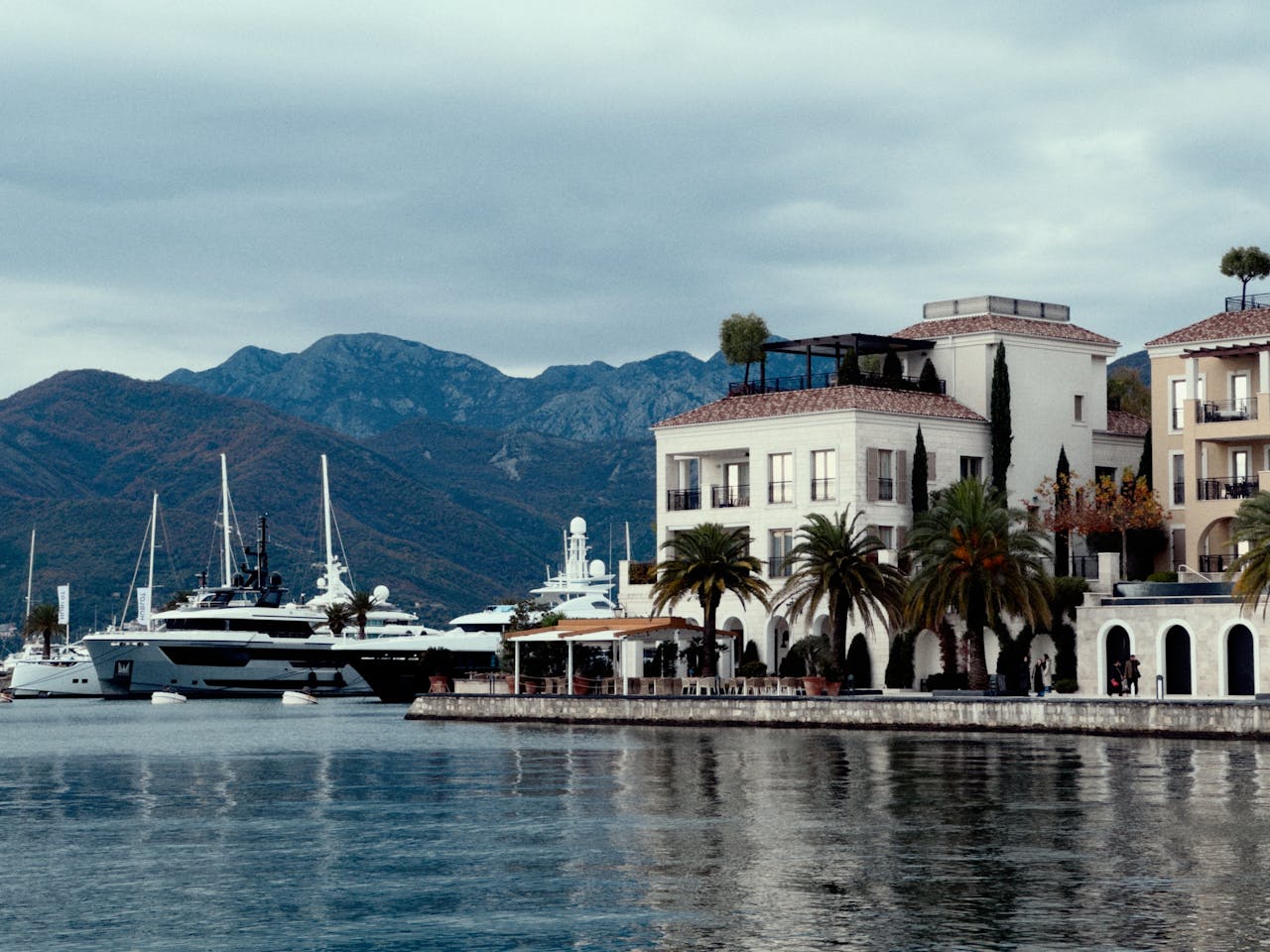 Elegant waterfront view with luxury yachts and scenic mountains in the background.