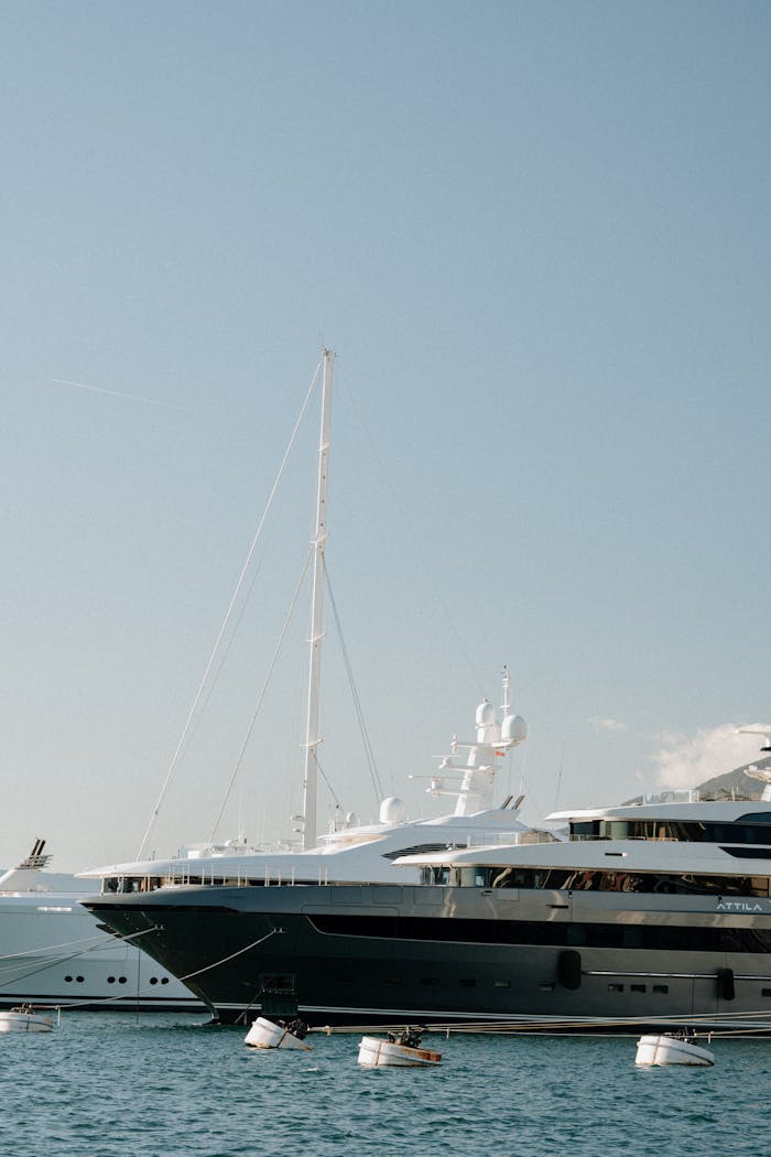 Scenic view of luxury yachts docked in the serene harbor of Perast, Montenegro under a clear sky.