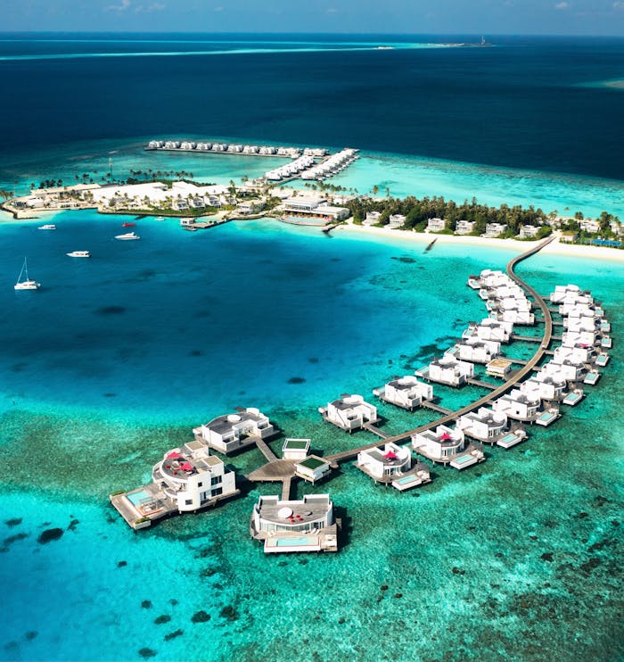 Aerial view of overwater villas in the Maldives showcasing turquoise waters and stunning resort scenery.